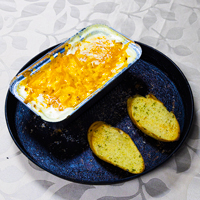   Livi Express Cheesy baked pasta in a tray served with two slices of garlic bread in Livingston.